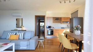 A modern living room with a sofa, a coffee table, and a dining area with chairs and a table.