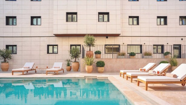 A poolside area with lounge chairs and potted plants. - Alora Hotel Mérida  (Mérida)