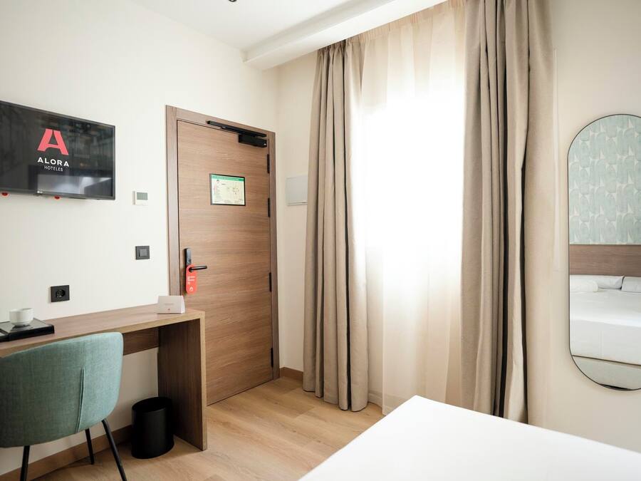 Una habitación de hotel con escritorio, silla, cama y un espejo grande.