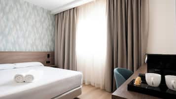 A hotel room with a bed, a desk with a coffee maker, cups, and a TV.