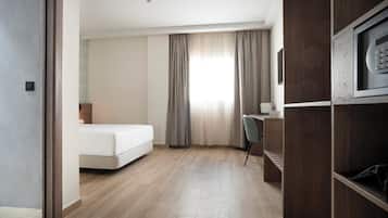 Una habitación de hotel con cama, escritorio, silla y televisión.