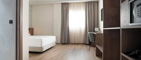A hotel room with a bed, a desk, a chair, and a TV.