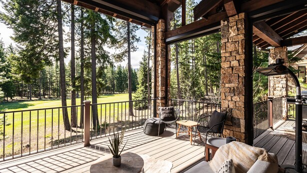 A covered outdoor deck with stone pillars, wooden flooring, and outdoor furniture. - This idyllic Suncadia home features a speakeasy, cowboy cold dip, outdoor shower, private library, chef's kitchen, golf course views, and MORE (Cle Elum)
