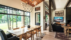 A spacious living area with a wooden dining table, comfortable seating, a large TV, and a fireplace. - This idyllic Suncadia home features a speakeasy, cowboy cold dip, outdoor shower, private library, chef's kitchen, golf course views, and MORE (Cle Elum)