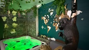 Una habitación con una bañera de hidromasaje verde, un mapa en la pared y una estatua de un mono.
