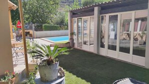 Un patio trasero con piscina, terraza techada y plantas en macetas.