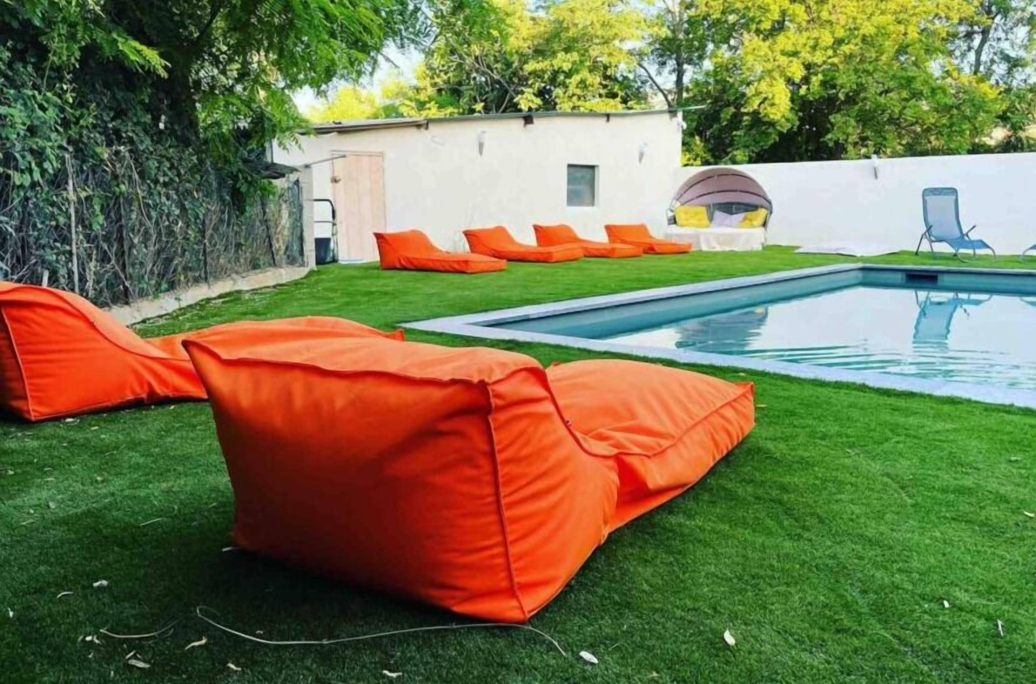 Una piscina con cojines naranja y una pared blanca al fondo.