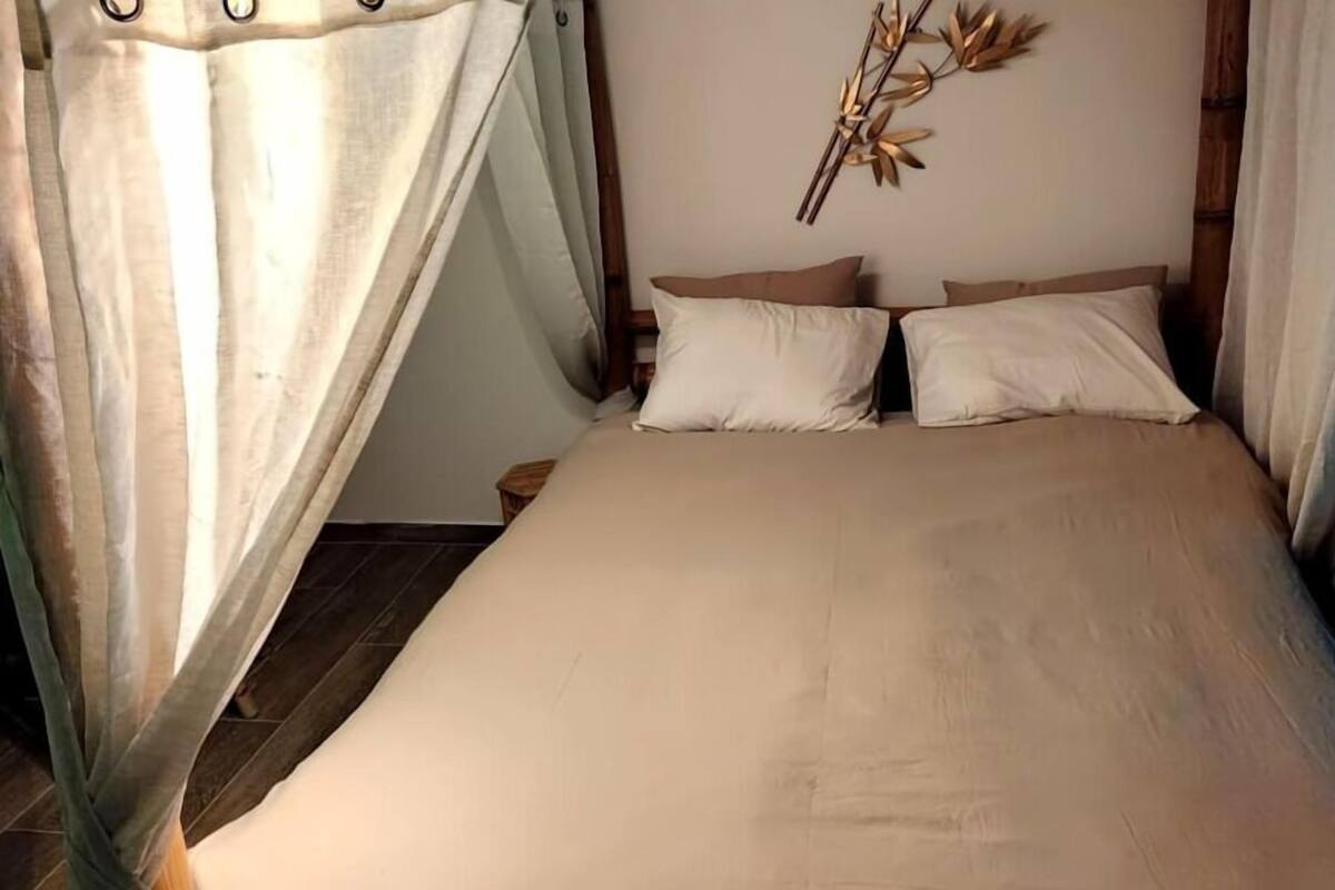 A bedroom with a bed, two pillows, a nightstand, and a wall decoration.