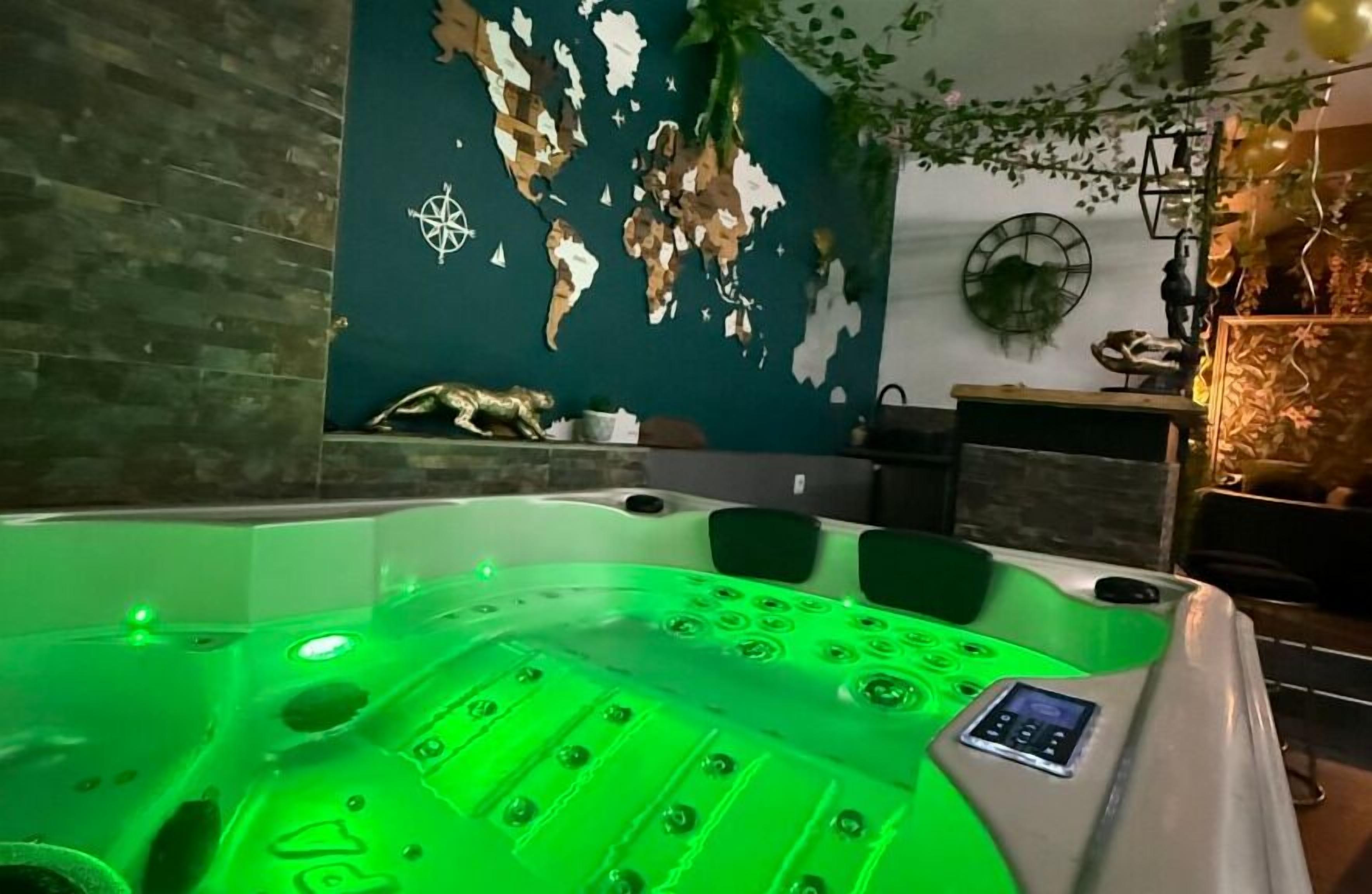 Ein Whirlpool mit grüner Beleuchtung, ein Wandbild mit einer Weltkarte und eine Uhr an der Wand.