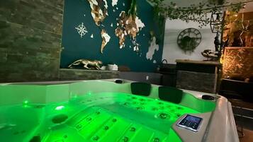 Ein Whirlpool mit grüner Beleuchtung, ein Wandbild mit einer Weltkarte und eine Uhr an der Wand.
