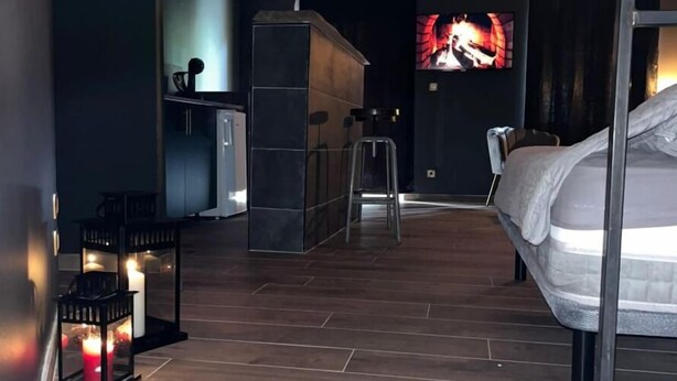 Una habitación de hotel moderna con cama, televisor, una pequeña kitchenette y zona de bar.