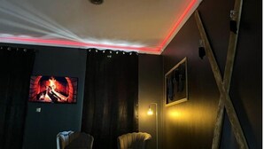 Una habitación con chimenea, dos sillones, una lámpara de pie y un cuadro en la pared.