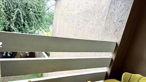 A balcony with a white railing and two green chairs. - Duke Mews Loft: Cozy 1-Bedroom Apartment in Sandton: 15 Mins to Sandton City. (Sandton)