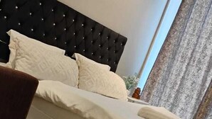 Una cama bien hecha con sábanas blancas en una habitación con cabecera capitonada.
