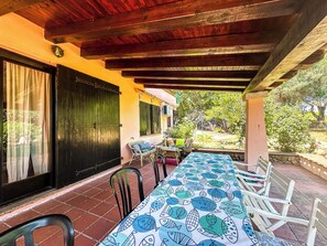 An outdoor patio with a long table covered in a fish pattern tablecloth, surrounded by chairs, and a wooden ceiling structure. - Villa with direct access to the ocean, exclusive 2,000 m² grounds, 3 bedrooms, 2 bathrooms. (Lu Impostu)
