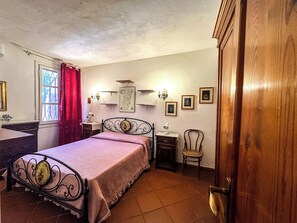 A bedroom with a bed, bedside table, lamp, chair, and a wooden wardrobe. - Villa with direct access to the ocean, exclusive 2,000 m² grounds, 3 bedrooms, 2 bathrooms. (Lu Impostu)