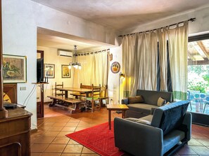 A living room with a sofa, a dining table, and a red rug. - Villa with direct access to the ocean, exclusive 2,000 m² grounds, 3 bedrooms, 2 bathrooms. (Lu Impostu)