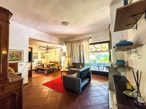 A living room with a sofa, a dining table, and chairs. There is a red rug on the floor. - Villa with direct access to the ocean, exclusive 2,000 m² grounds, 3 bedrooms, 2 bathrooms. (Lu Impostu)