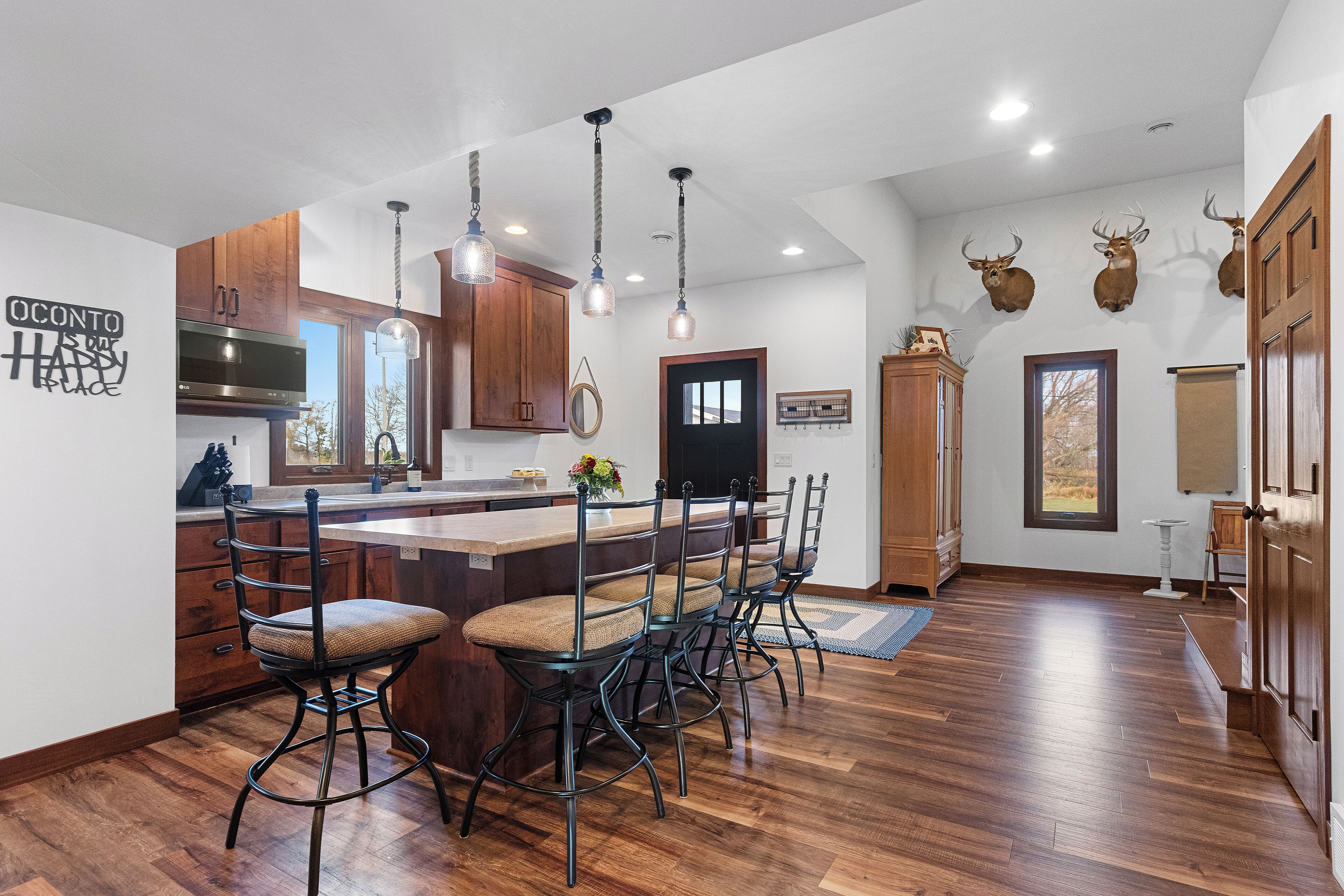 A modern kitchen with a central island, wooden cabinets, and pendant lighting.