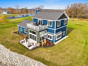 Une maison à deux étages dotée d’un balcon, d’une terrasse couverte et offrant une vue sur un lac.