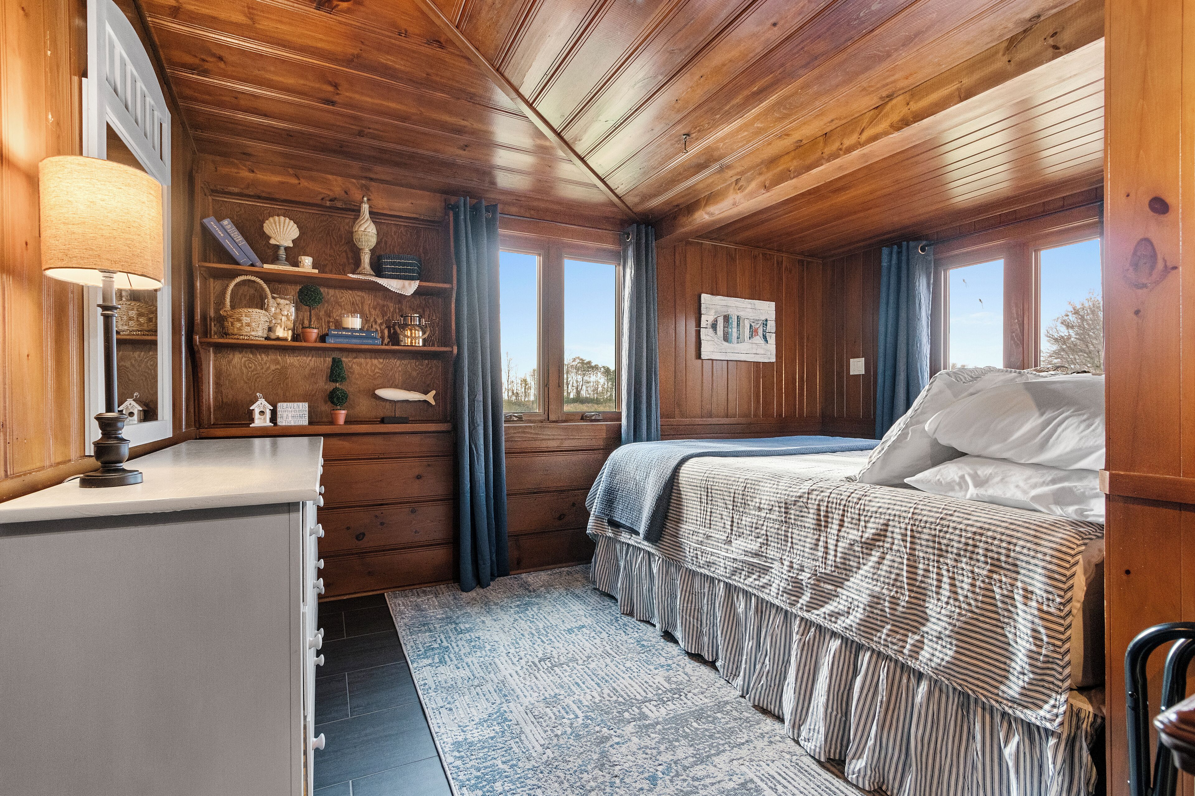 Een houten kamer met een bed, bureau en raam.