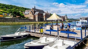 Un muelle a orillas del río con barcos, un edificio histórico y una carpa.