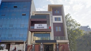 A modern hotel named 'Hotel Black Rose' with a glass facade, a signboard, and a gated entrance. - Hotel Black Rose (New Delhi)