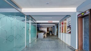 A modern hotel reception area with a glass wall, a reception desk, and a sign indicating premium rooms with modern furniture. - Hotel Black Rose (New Delhi)