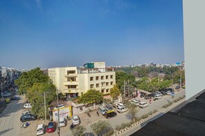 A multi-story building with a flat roof, surrounded by parked cars and trees. - Hotel Black Rose  (New Delhi)