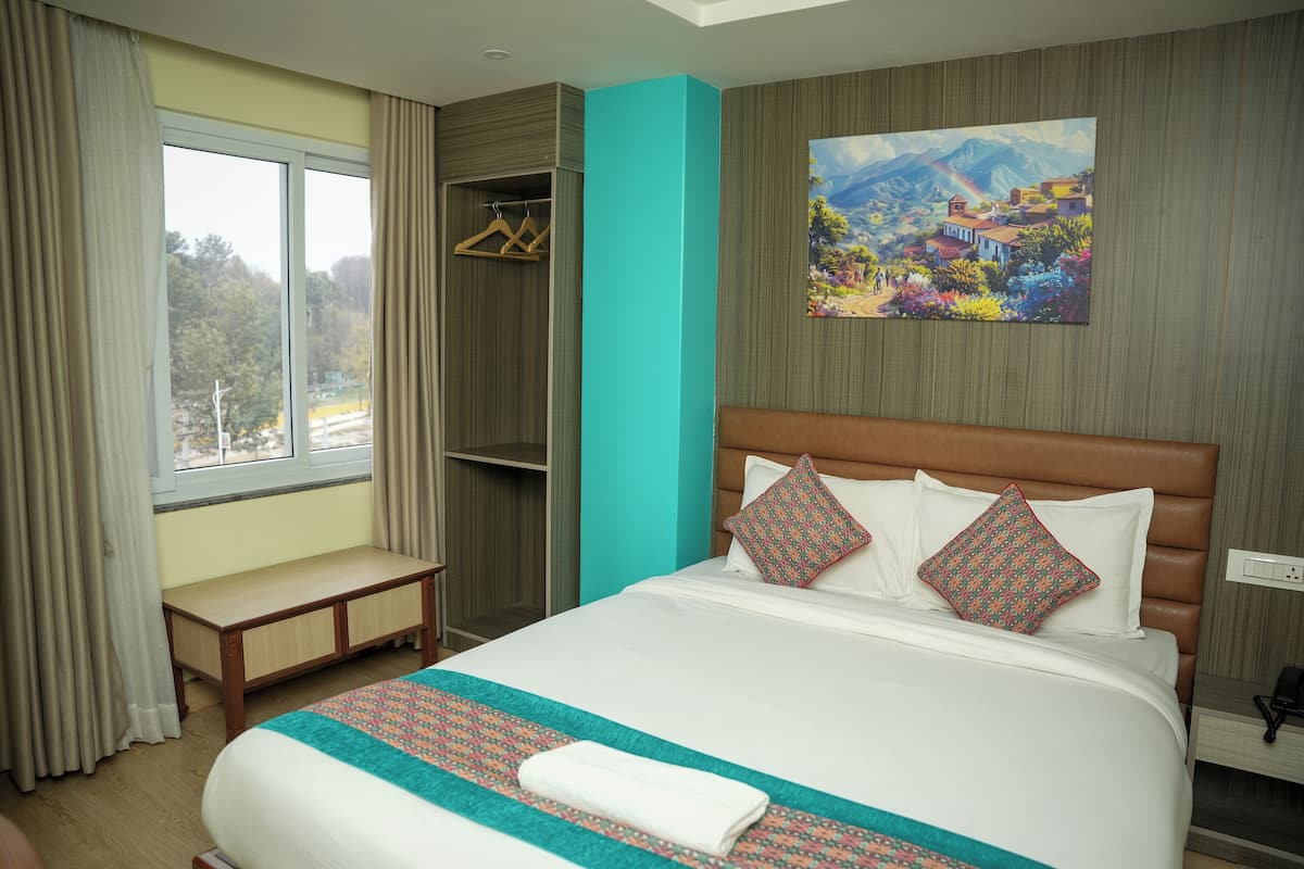 A hotel room with a large bed, a bench, a wardrobe, and a painting on the wall.