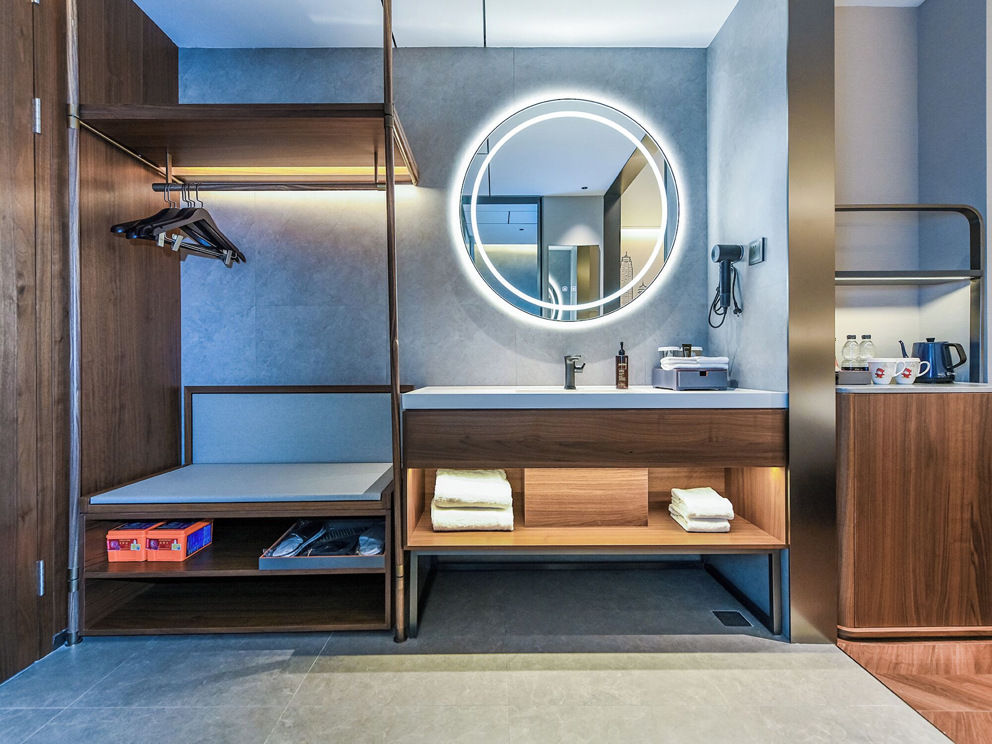 Ein modernes Badezimmer mit einem Holzkosmetikschrank, einem runden Spiegel mit Beleuchtung und einer integrierten Ablage mit Handtüchern.
