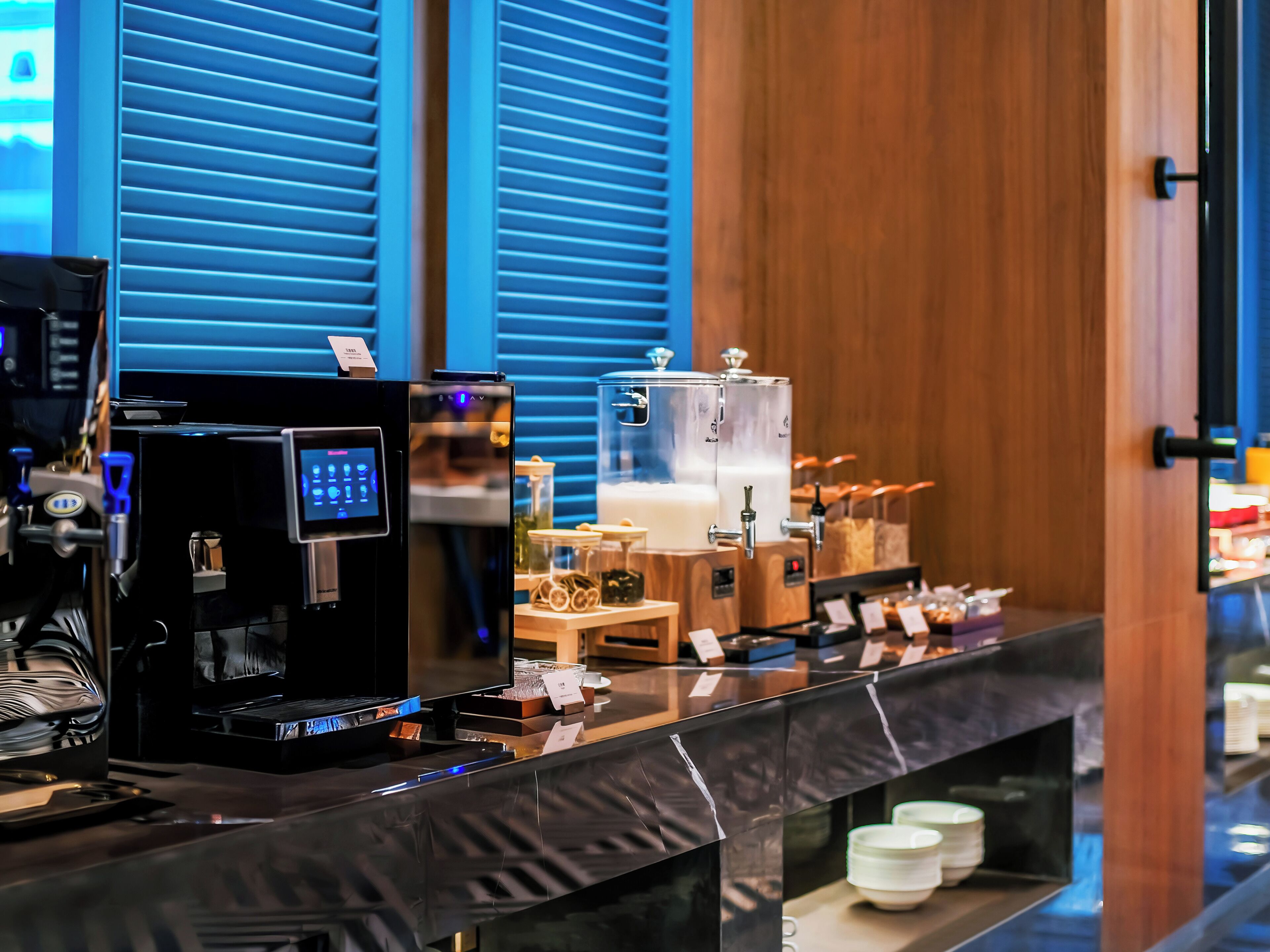 Una estación de café con cafetera, espumador de leche y dispensador de agua.