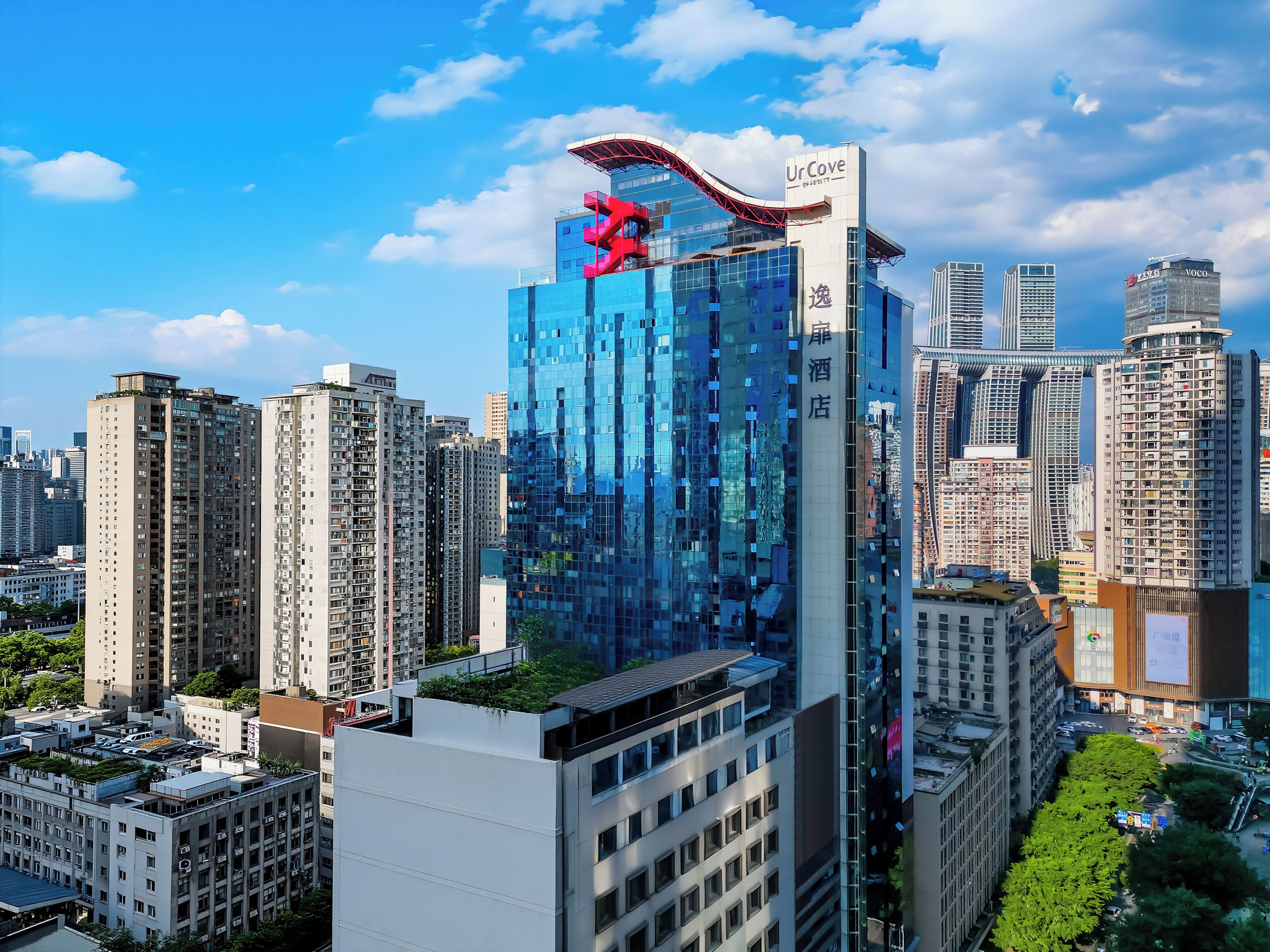 Un hotel de gran altura con una escultura roja distintiva en la parte superior, rodeado de otros edificios altos.