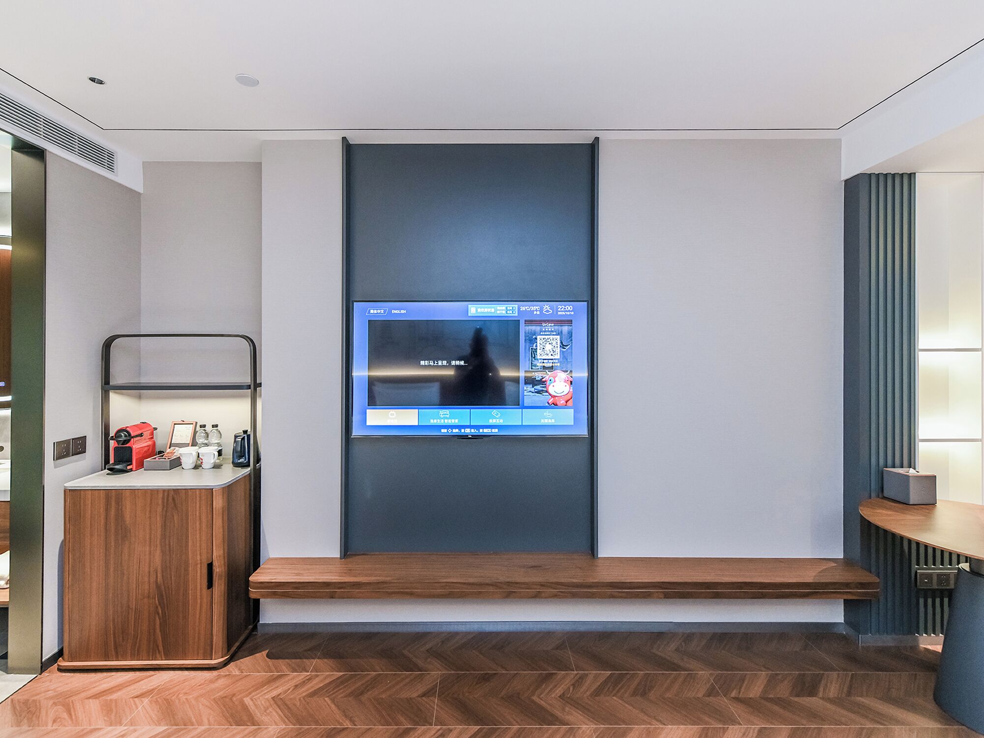 Une chambre d’hôtel moderne équipée d’un téléviseur intégré, d’une armoire en bois et d’un banc.