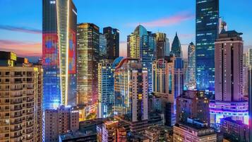 A cityscape with modern high-rise buildings, some with illuminated signage.