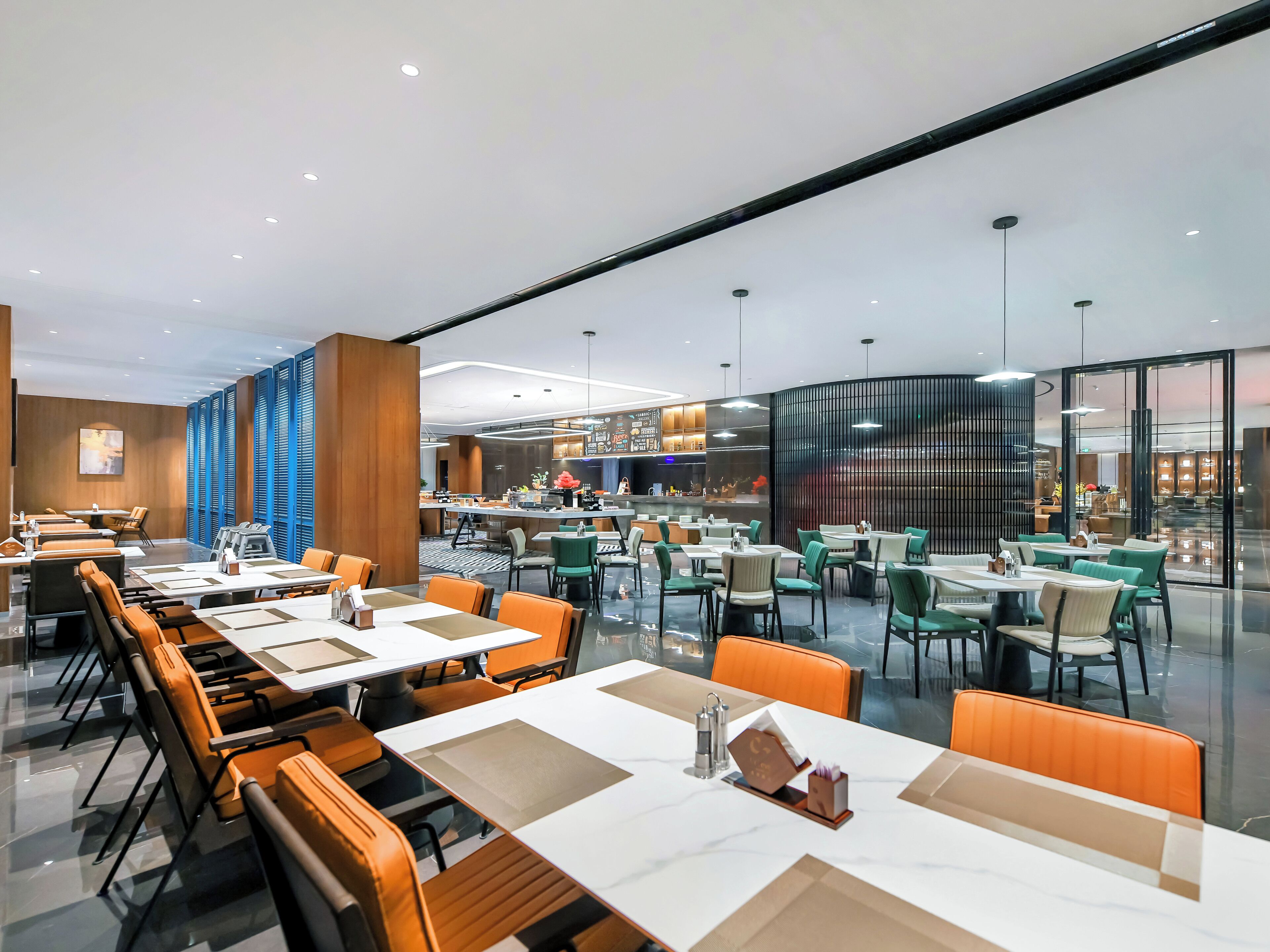 A modern restaurant with multiple dining areas, including a bar and a buffet.