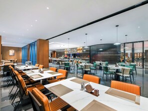 En moderne restaurant med flere spiseområder, heriblandt en bar og et buffetbord.