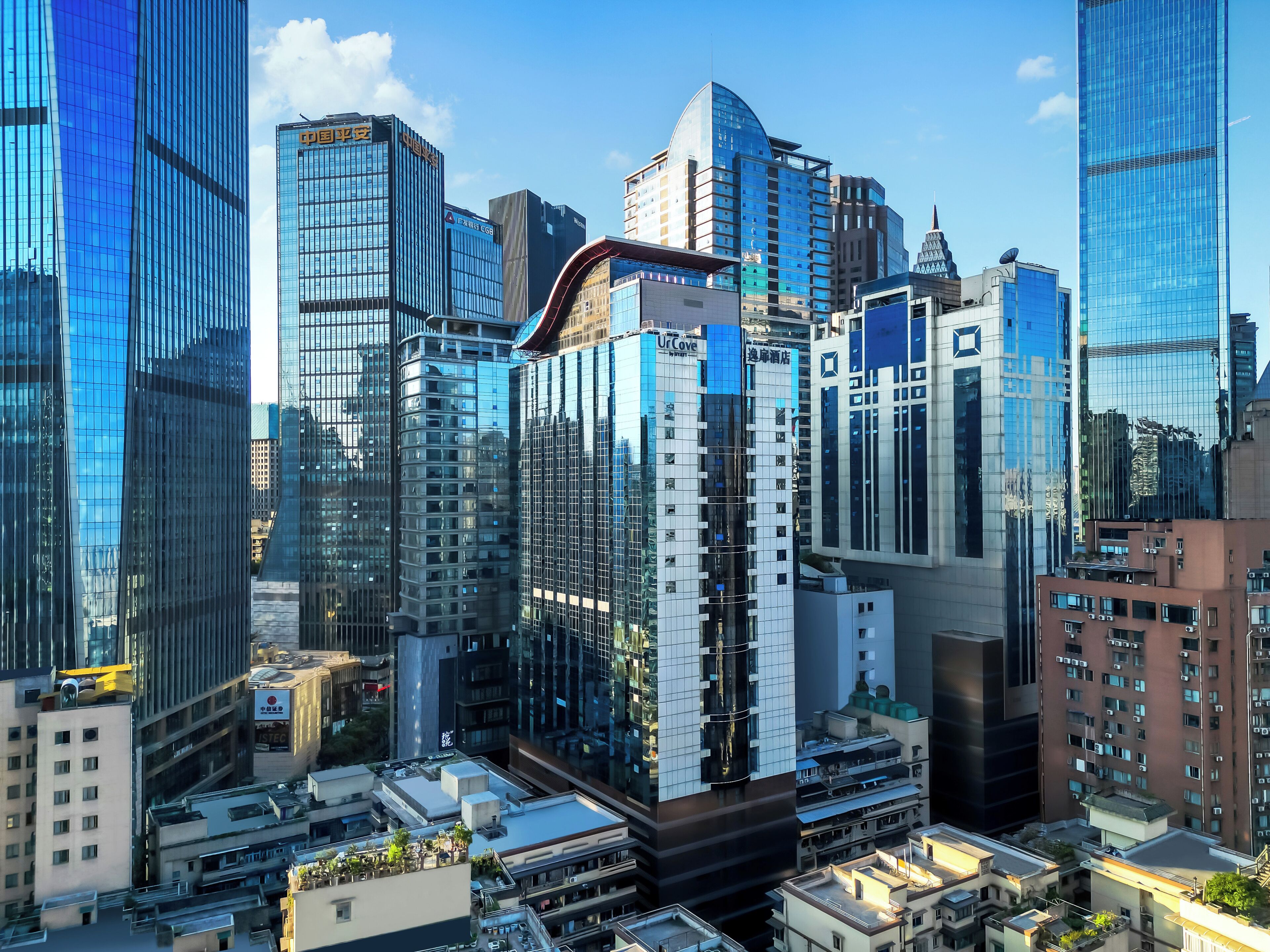 Un paysage urbain avec des immeubles modernes de grande hauteur, dont un hôtel remarquable à la façade blanche et bleue distinctive.