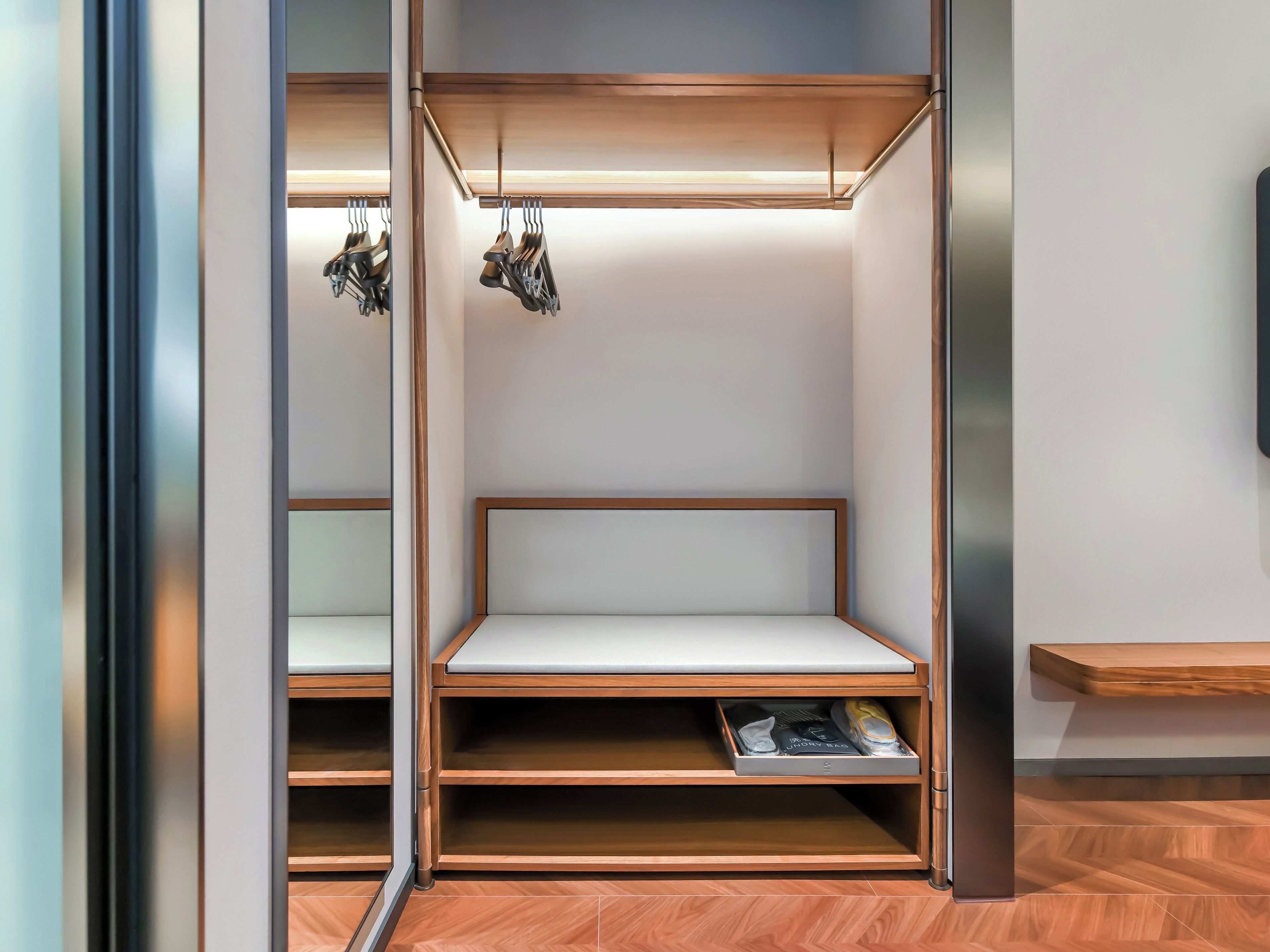 A modern closet with built-in shelves, a hanging shoe rack, and a bench.