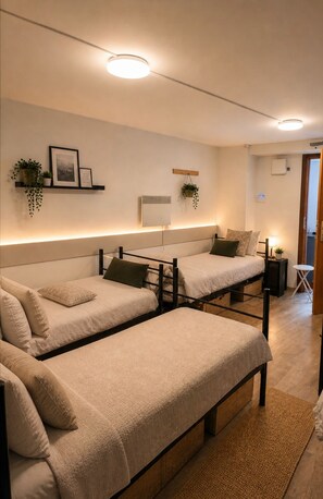 Une chambre d’hôtel avec deux lits simples, une table de chevet avec une lampe, une petite plante en pot, un climatiseur fixé au mur et une étagère avec des photos encadrées et des plantes.