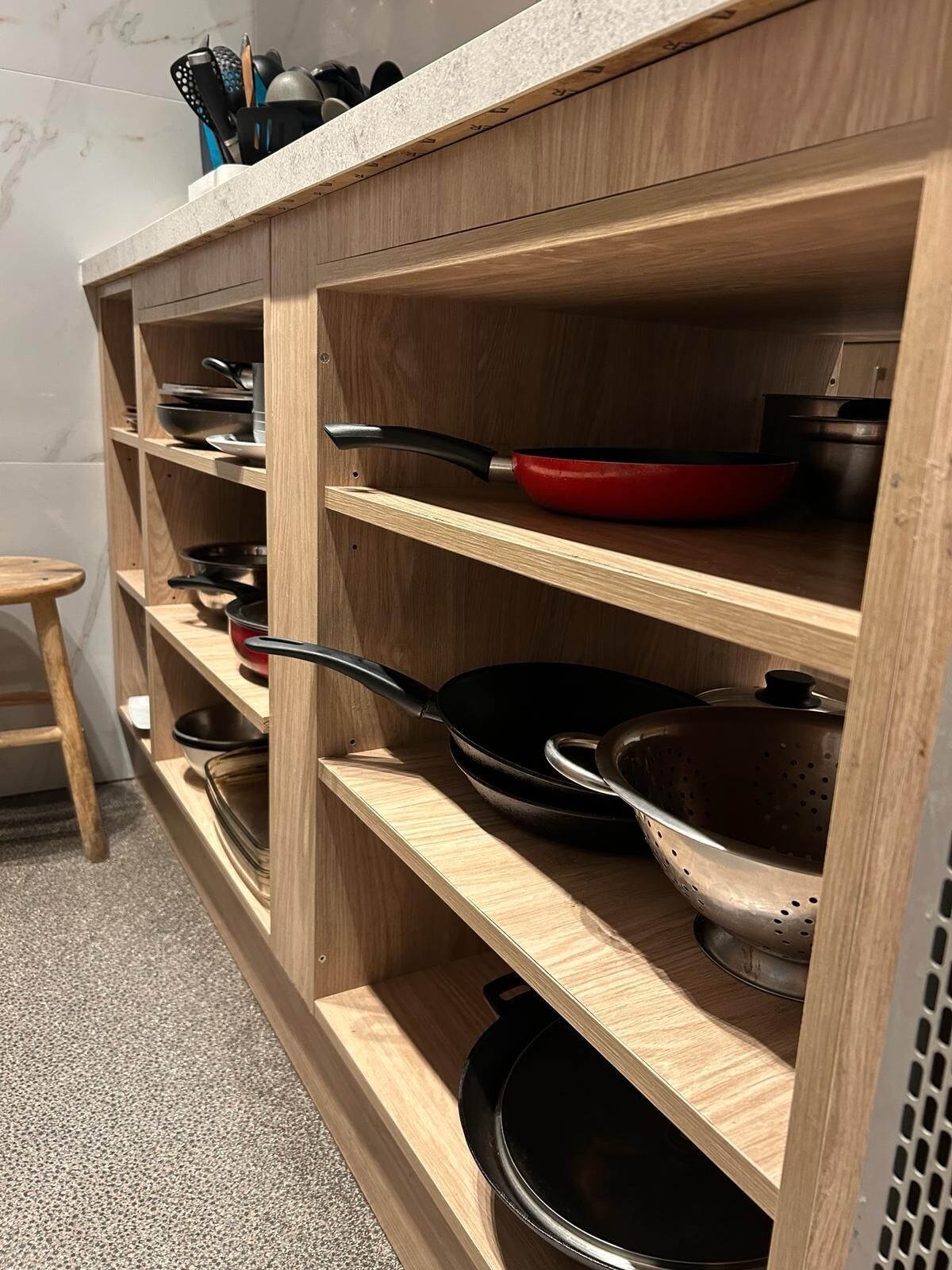 A kitchen with wooden shelves holding various cookware and utensils.