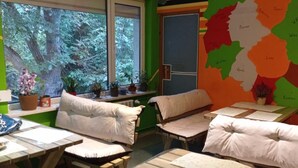 Ein Zimmer mit zwei Betten, einem Fenster mit Blick auf Bäume, einer Karte an der Wand und einem kleinen Tisch mit Papieren.