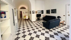 Una sala de estar con un sofá negro, un televisor y un comedor con una mesa y sillas.