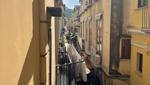 Un estrecho callejón flanqueado por edificios, con balcones y una pequeña tienda al final.
