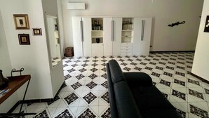 Una habitación con sofá negro, armario blanco y suelo de baldosas estampadas.