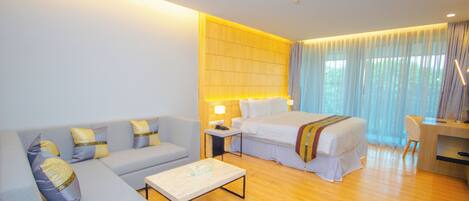 Una habitación de hotel con sofá, cama, escritorio y una mesa de centro.