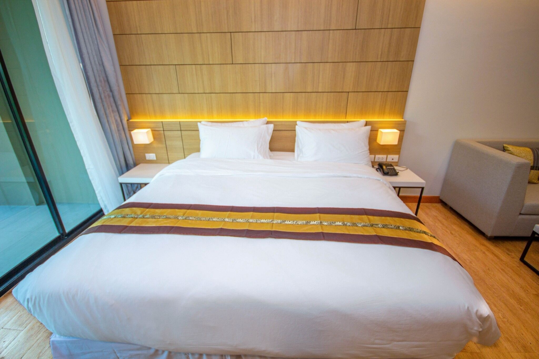 A hotel room with a large bed, two bedside tables, a chair, and a view of the outside.