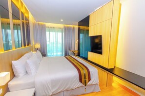 A hotel room with a large bed, a flat-screen TV mounted on the wall, and a view of the city through the window. - The Grand Chaiyapruek Nimman Chiangmai (Chiang Mai)