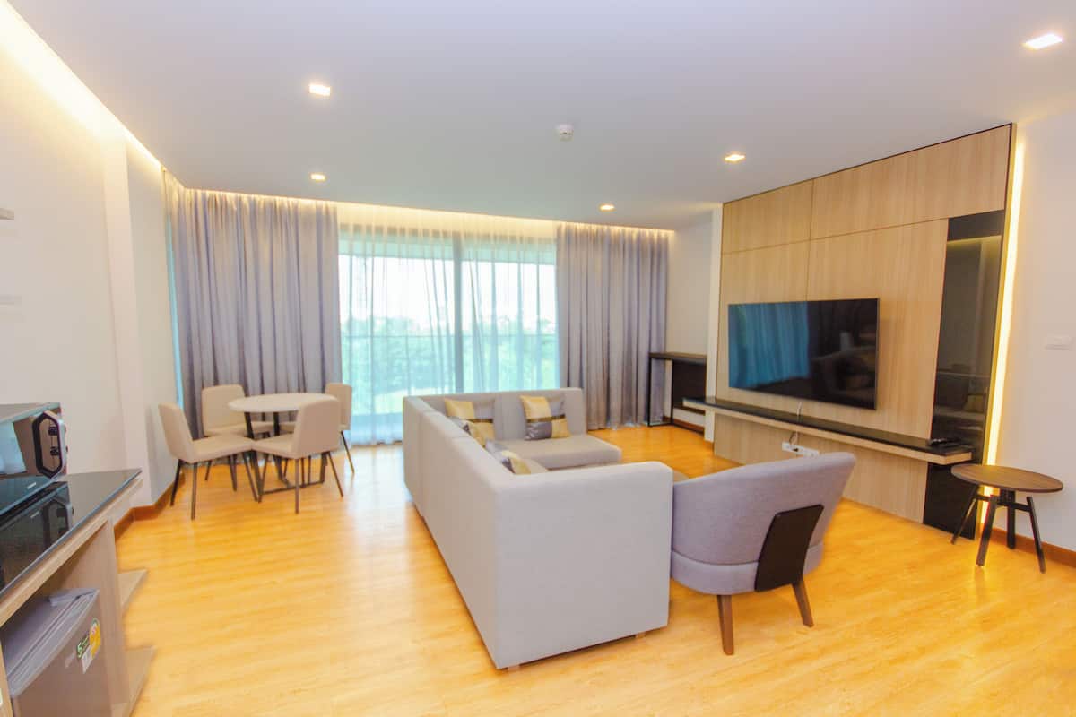 A modern living room with a sofa, chairs, a TV, and a dining area.