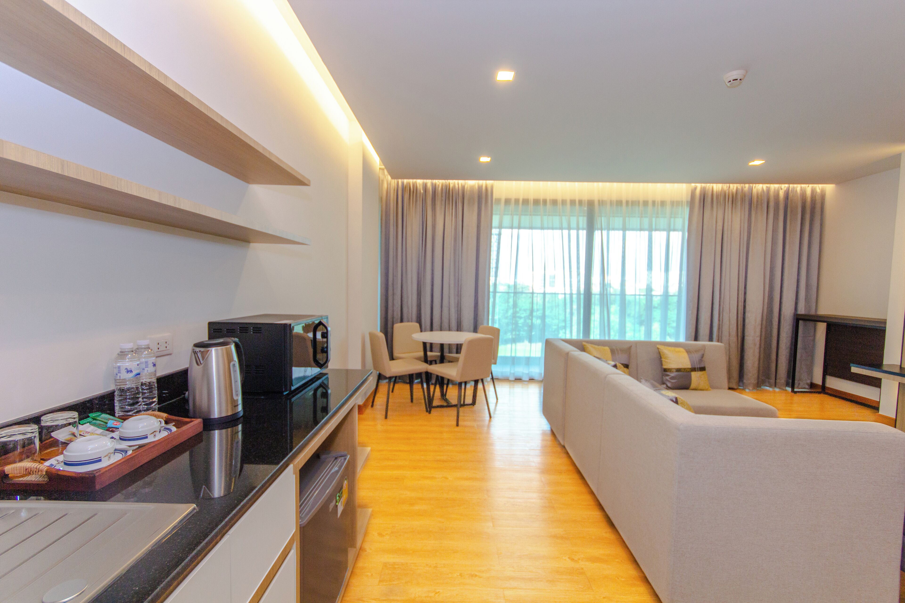 Une chambre d’hôtel moderne dotée d’une kitchenette, d’un coin repas et d’un espace de vie avec un canapé et une télévision.